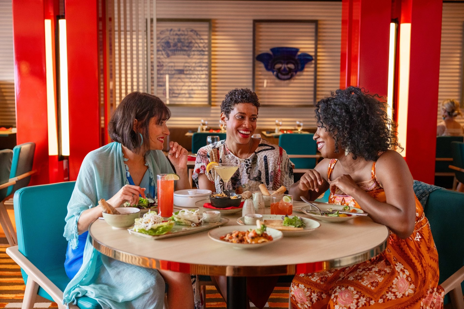 Carnival FunPacks, specialty dining Three friends sharing dishes and cocktails at a specialty restaurant on a Carnival ship