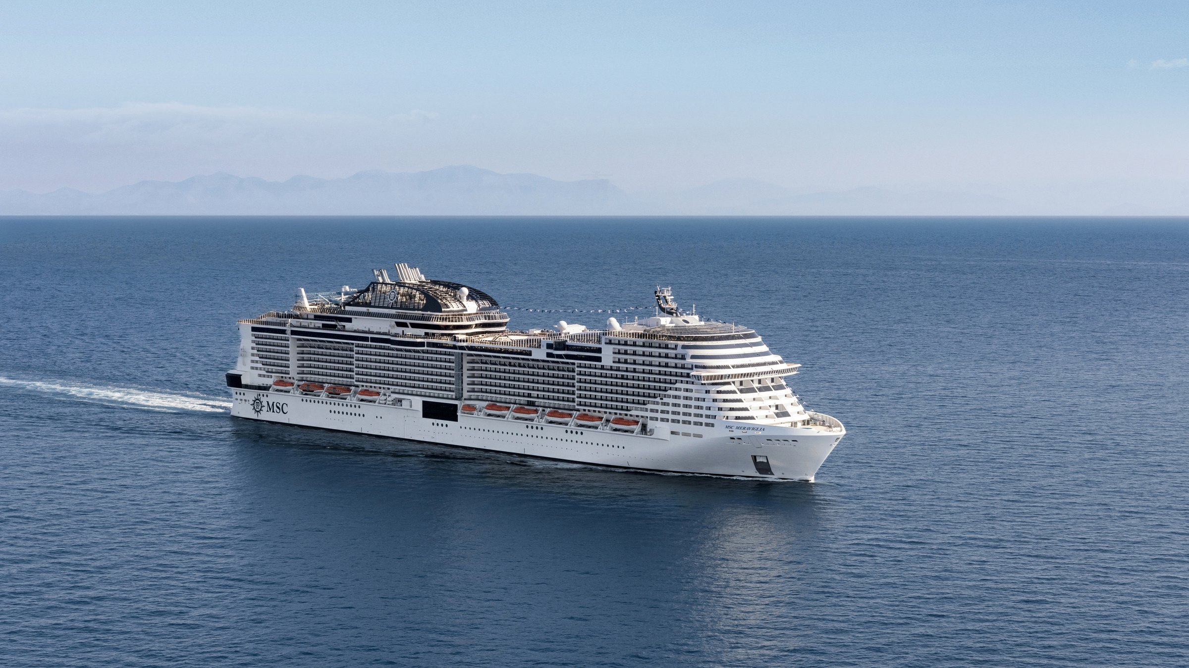 MSC Meraviglia at sea MSC Meraviglia sailing on a calm sea, with mountains on the horizon
