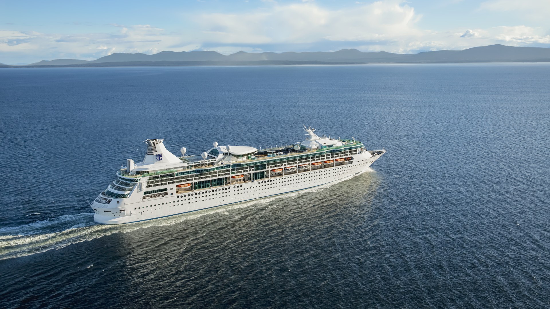 Rhapsody of the Seas at sea Rhapsody of the Seas sailing at sea, with mountains on the horizon
